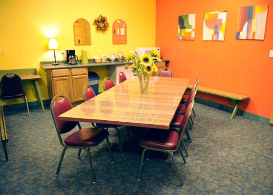Long Table with 9 chairs, a bench, a desk, and a kitchenette with a microwave and coffee maker at Dance Center Evanston